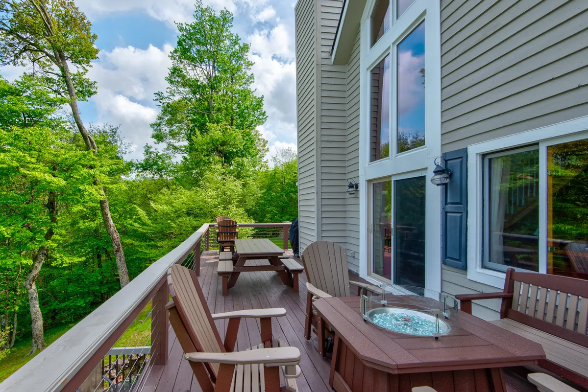 A cozy outdoor seating area on the deck surrounded by greenery, featuring a fire pit for evening gatherings. The tranquil setting is perfect for relaxing, making s’mores, or stargazing after an active day.