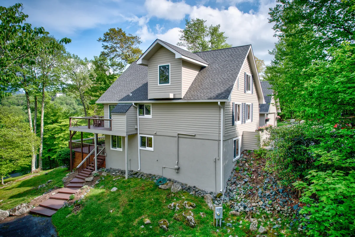 A view of the home's deck overlooking lush greenery and rock landscaping, offering a serene spot to relax after a day of adventure. The outdoor space is ideal for gatherings, enjoying sunset views, or simply soaking up the peaceful surroundings.